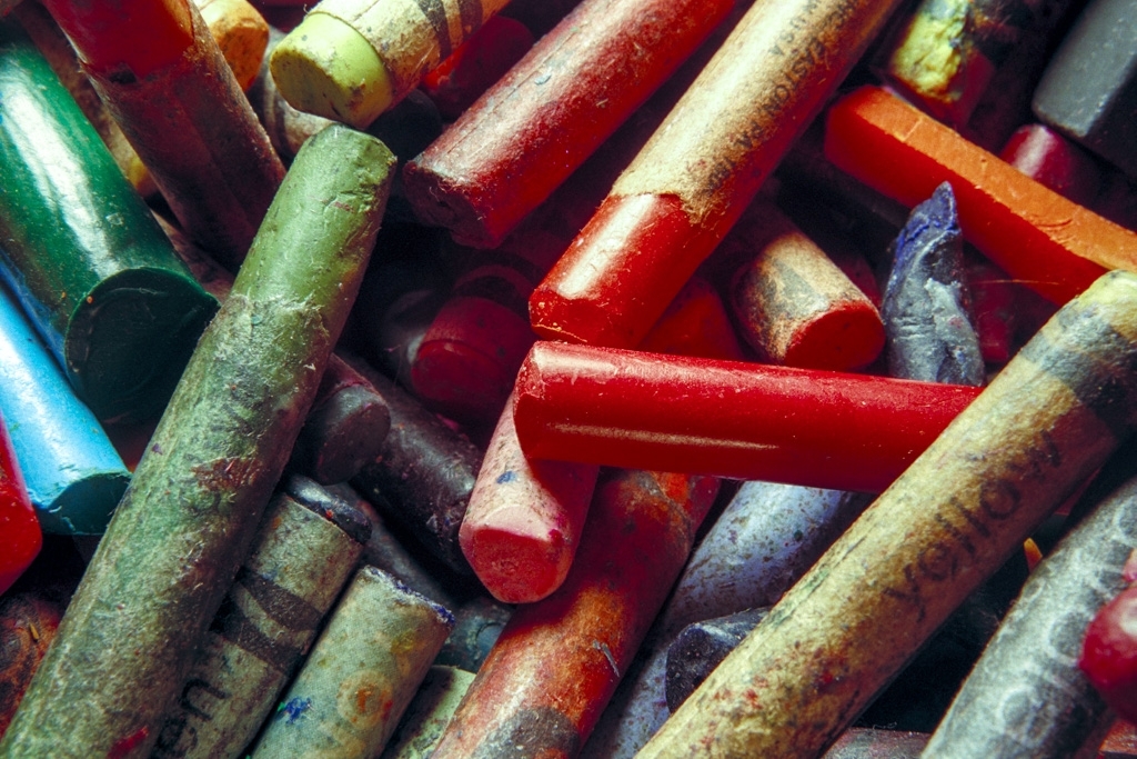 Crayons photograph. Dirty and worn crayons. Bright red crayon in the center; green on the left; yellow on the right.