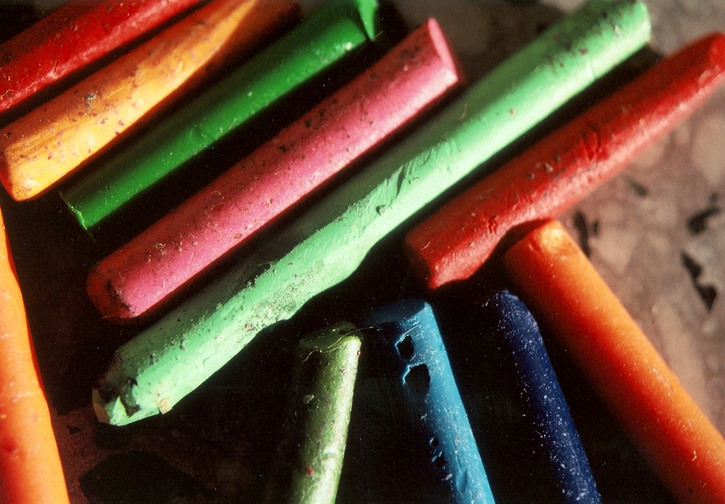 Crayons photograph. Crayons, peeled and lying in the sun. Green, pink, orange, and blue.