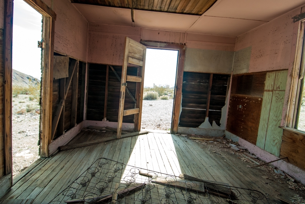 Death Valley, California photograph. Interior of a crumbling building with fading teal and pink paint and missing doors. 