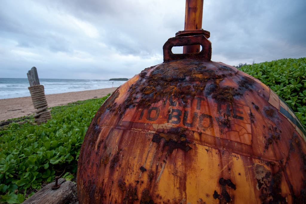 Kauai, Hawaii photograph. Large buoy at the entrance to a fairly large beach. Open fires were allowed at this beach, and we met a friendly older couple as they rolled joints in their car, watching the sunset. We were amazed at how much the surfers could tolerate the cold, at this beach.