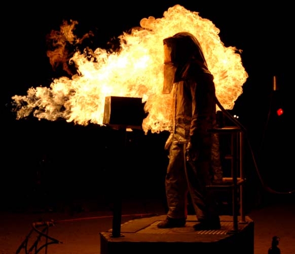 Burning Man 2005 photograph. People in proximity suits, being flamed by flamethrowers, while they dance! A project of Interpretive Arson. See <a href='/fire/dancedanceimmolation/dance-dance-immolation-watching-fire/'>the full set of photos of Dance Dance Immolation</a>.
